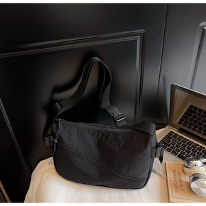 Detailed shot of black nylon shoulder bag with adjustable strap and zip pocket