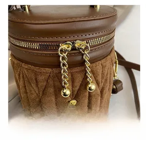 Detailaufnahme der goldenen Reißverschlüsse und Steppmuster auf der braunen Beuteltasche