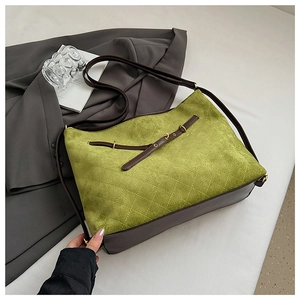 Close-up of quilted suede texture and leather strap on a vintage green tote bag
