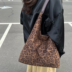Grand sac cabas seau à motif léopard en daim porté à l'épaule par un mannequin chic