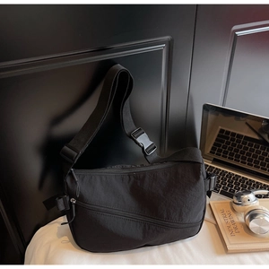 Close-up of black nylon dumpling bag with adjustable shoulder strap and plastic buckle