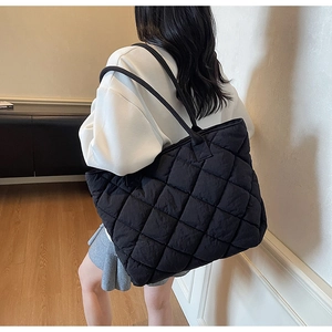 Détail d'un grand sac cabas matelassé noir avec coutures en losanges sur mannequin