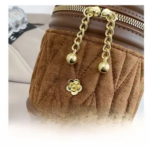 Detailansicht der braunen Wildleder-Eimertasche mit Steppmuster und Metallblumen-Dekor