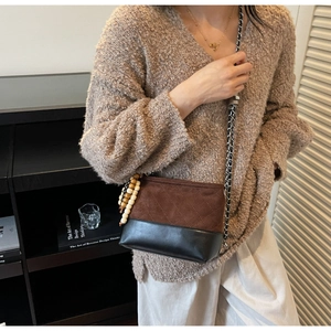 Detail of a retro quilted crossbody bag in brown suede and black leather with wooden beads