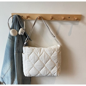 Detail of white quilted tote bag featuring a diamond pattern and adjustable strap