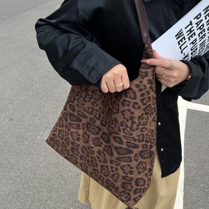 Vue détaillée du sac seau en toile léopard avec bandoulière en cuir marron porté par un mannequin