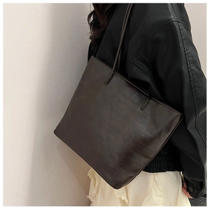 Side view of a vintage brown large capacity faux leather tote bag worn by a model