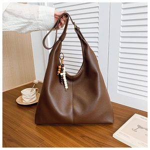 Detail of dark brown lychee textured leather tote with wooden bead tassel and wide strap
