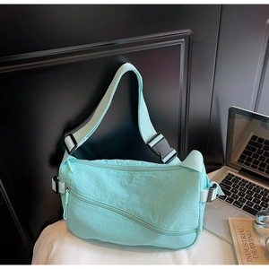 Detail view of mint green nylon crossbody bag with multiple zippers and adjustable strap