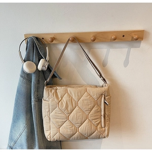 Detail of beige quilted tote bag showing diamond stitch pattern and side zipper pocket