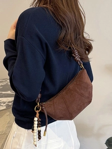 Brown suede half-moon crossbody bag with leather knot strap and beaded pendant detail