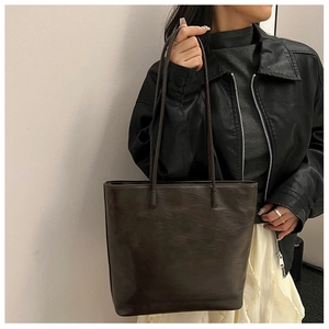 Model wearing a dark brown vintage leather tote bag with a minimalist shoulder strap design