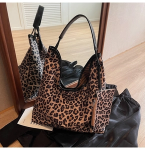 Detail of leopard print tote bag with black leather straps and matching small pouch charm