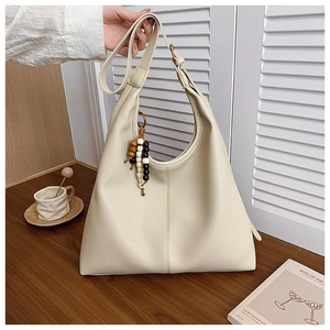 Close-up of cream Hobo bag with lychee texture and wooden beaded tassel detail