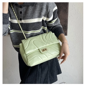 Close-up of mint green quilted bag with golden twist lock and chain strap details