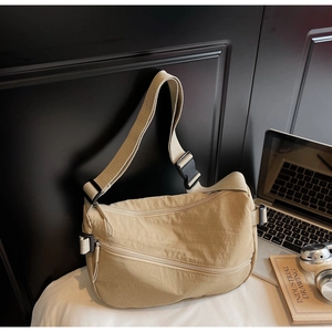 Detailed view of khaki nylon crescent bag with adjustable strap and front zipper pocket