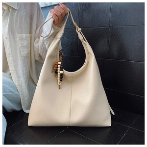 Detail of cream tote bag with lychee texture and colorful wooden bead charms