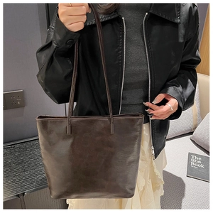 Detail of vintage dark brown faux leather tote bag with soft texture and long straps