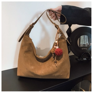 Detail of caramel suede shoulder bag with bohemian tassel and brand embossed logo