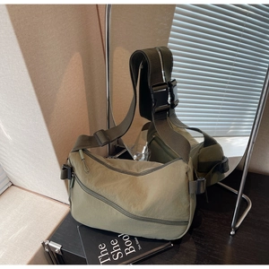 Detail of army green nylon shoulder bag with multiple zippered pockets and adjustable wide strap