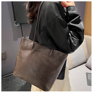 Close-up of the large brown tote bag showing vintage leather texture and side capacity