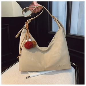 Detail of matte cream hobo bag featuring embossed MERFIL logo and colorful charm accessories