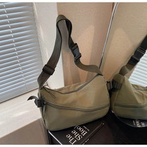Detail of army green nylon crescent bag with wide strap reflecting in mirror surface