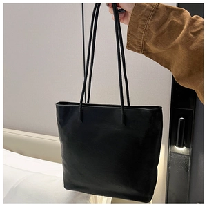 Detail of minimalist black faux leather tote bag with fine texture and slim dual straps