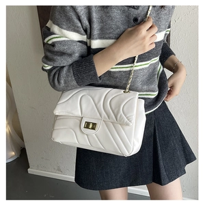 White quilted chain bag with gold hardware worn by model in casual striped knitwear