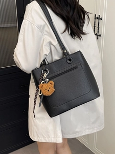 Elegant black pebbled leather tote bag with teddy charm and scarf, side-view on model