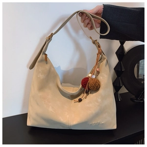 Detail of a creamy beige frosted hobo bag with a decorative tassel and MERFIL logo