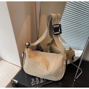 Detail of khaki nylon shoulder bag featuring functional zip pockets and adjustable strap