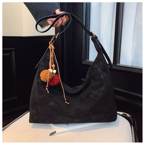 Detail of black matte suede Hobo bag with brand embossing and colorful pompom charms