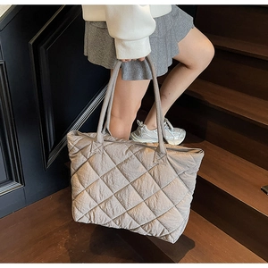 Détail d'un grand sac cabas matelassé gris avec motif losanges sur escalier