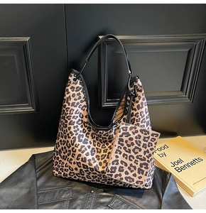 Detail view of large leopard print tote bag with matching mini pouch on black leather