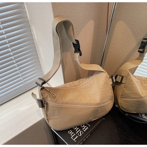 Detailed texture of beige nylon crescent bag featuring wide shoulder strap and buckles