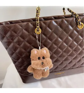 Détail d'un bijou de sac chien en peluche avec collier de perles sur un cabas matelassé