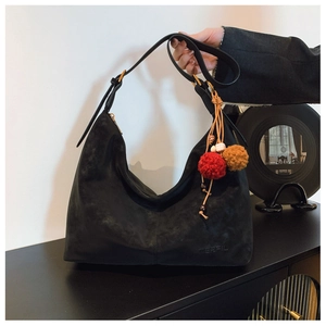Detail of black matte hobo bag with colorful pom-pom charm and Merfil logo branding