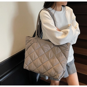 Détail de la texture matelassée d'un grand sac cabas gris en nylon dans un cadre décontracté
