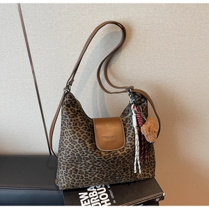 Détail du sac cabas en toile léopard avec rabat en cuir et pendentif ours décoratif