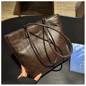 Detailed view of dark brown glossy leather tote bag with natural wrinkled texture