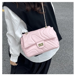 Detail of pink quilted chain bag with gold twist lock on street photography background