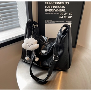 Detailed close-up of black pleated crescent shoulder bag with white cloud charm on silver table