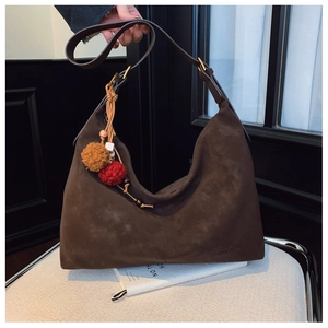 Detail of brown suede oversized hobo bag with tassel charms and DIERAIL branding