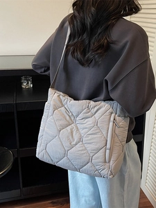 Quilted dark grey oversized tote bag with diamond pattern shown on model's shoulder
