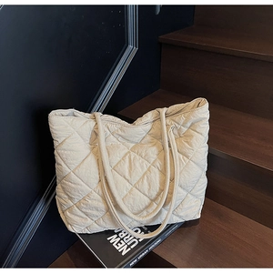Vue détaillée d'un sac cabas beige matelassé avec motif à carreaux sur un décor sombre