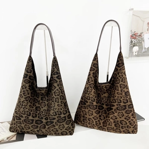 Détail de deux sacs cabas en daim à motif léopard avec des poignées en cuir brun