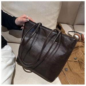 Detail of dark brown tote bag showing smooth leather texture and long shoulder straps