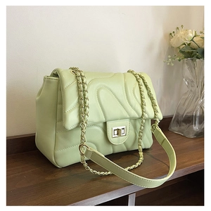Detailed macro view of mint green quilted shoulder bag with golden twist-lock and chain