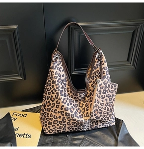 Detail view of leopard print tote bag with matching zippered pouch and brown leather straps